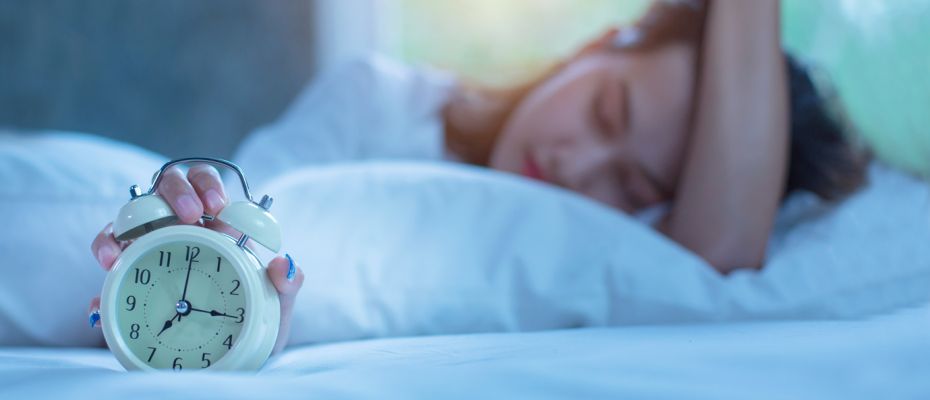 woman sleeping while holding alarm clock